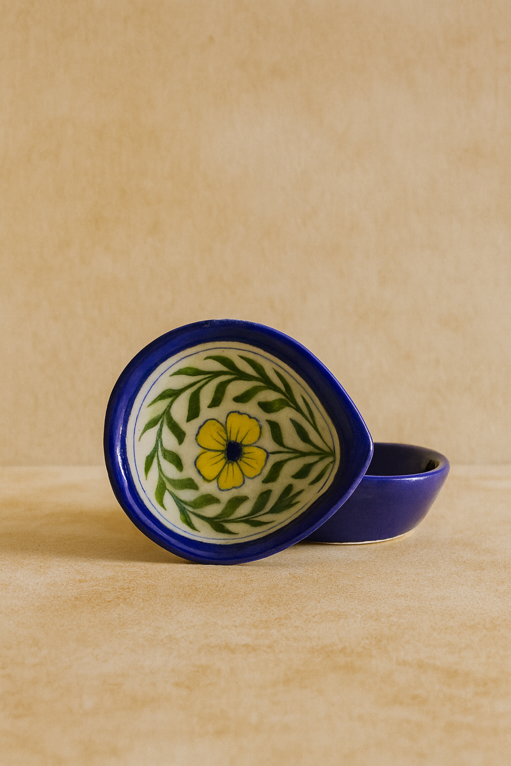 Ceramic diya with floral design on a beige background