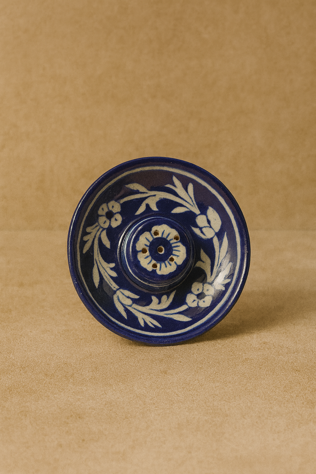 Blue ceramic incense holder with white floral pattern on a brown background