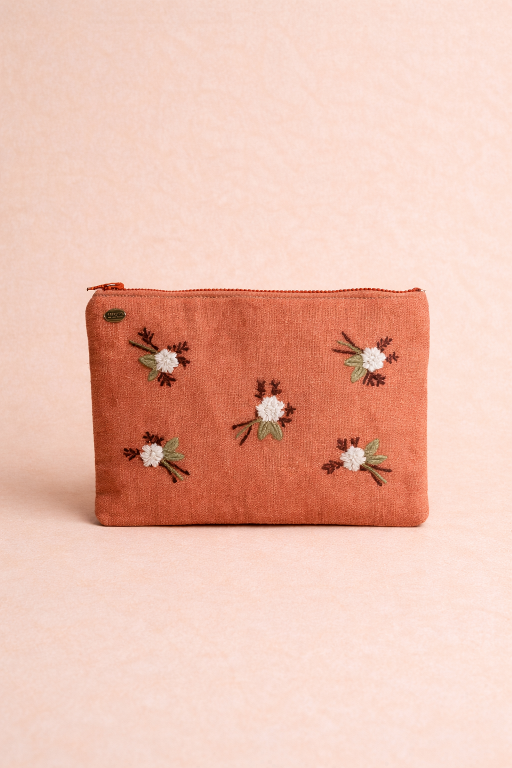 Orange pouch with floral embroidery on a pink background