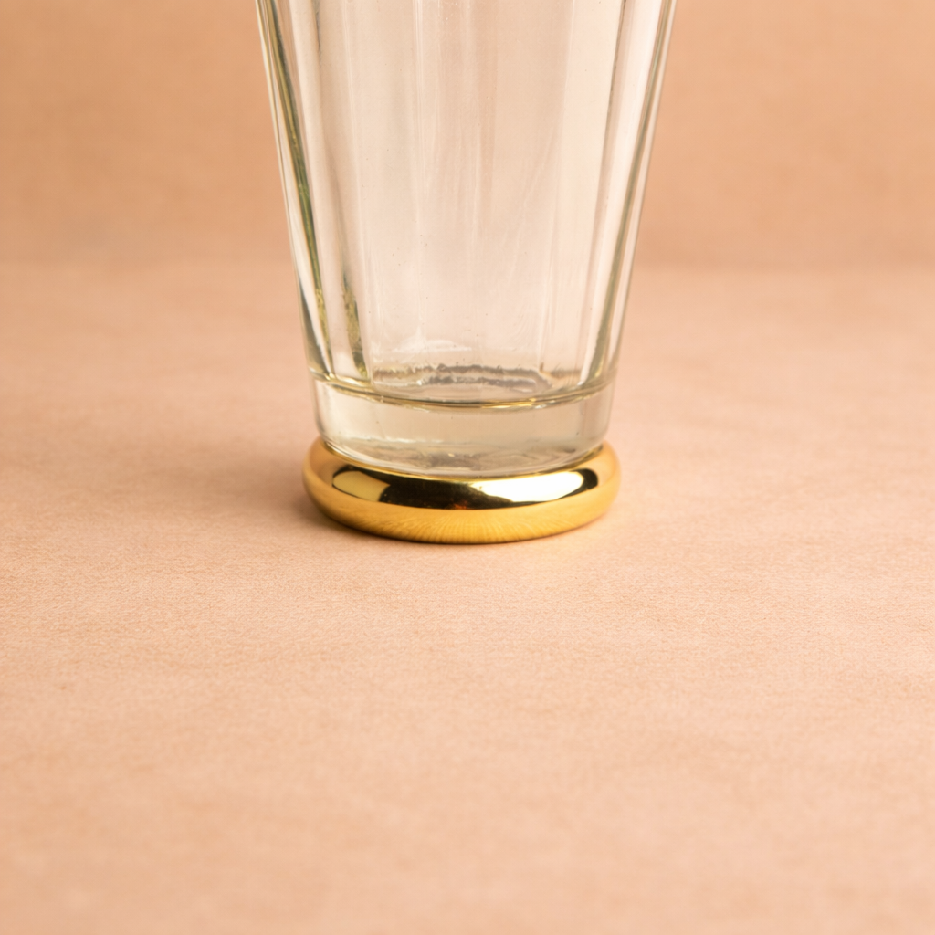 Clear glass with gold base on a beige background