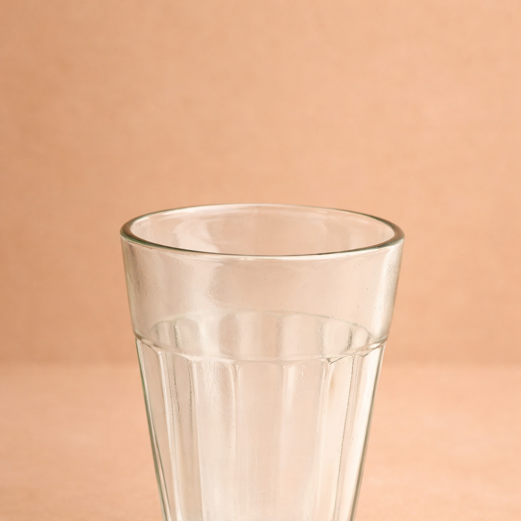 Clear glass tumbler on a peach background