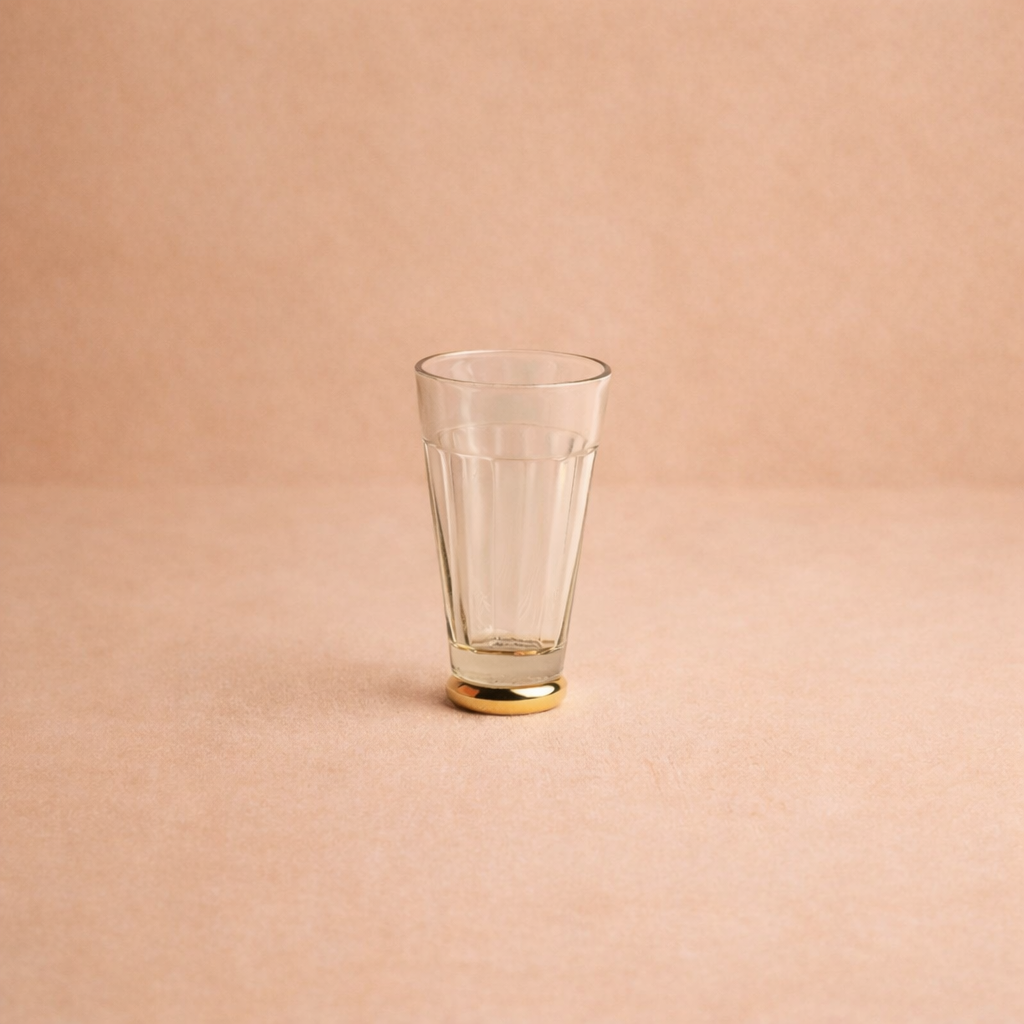 Clear glass with gold base on a beige background