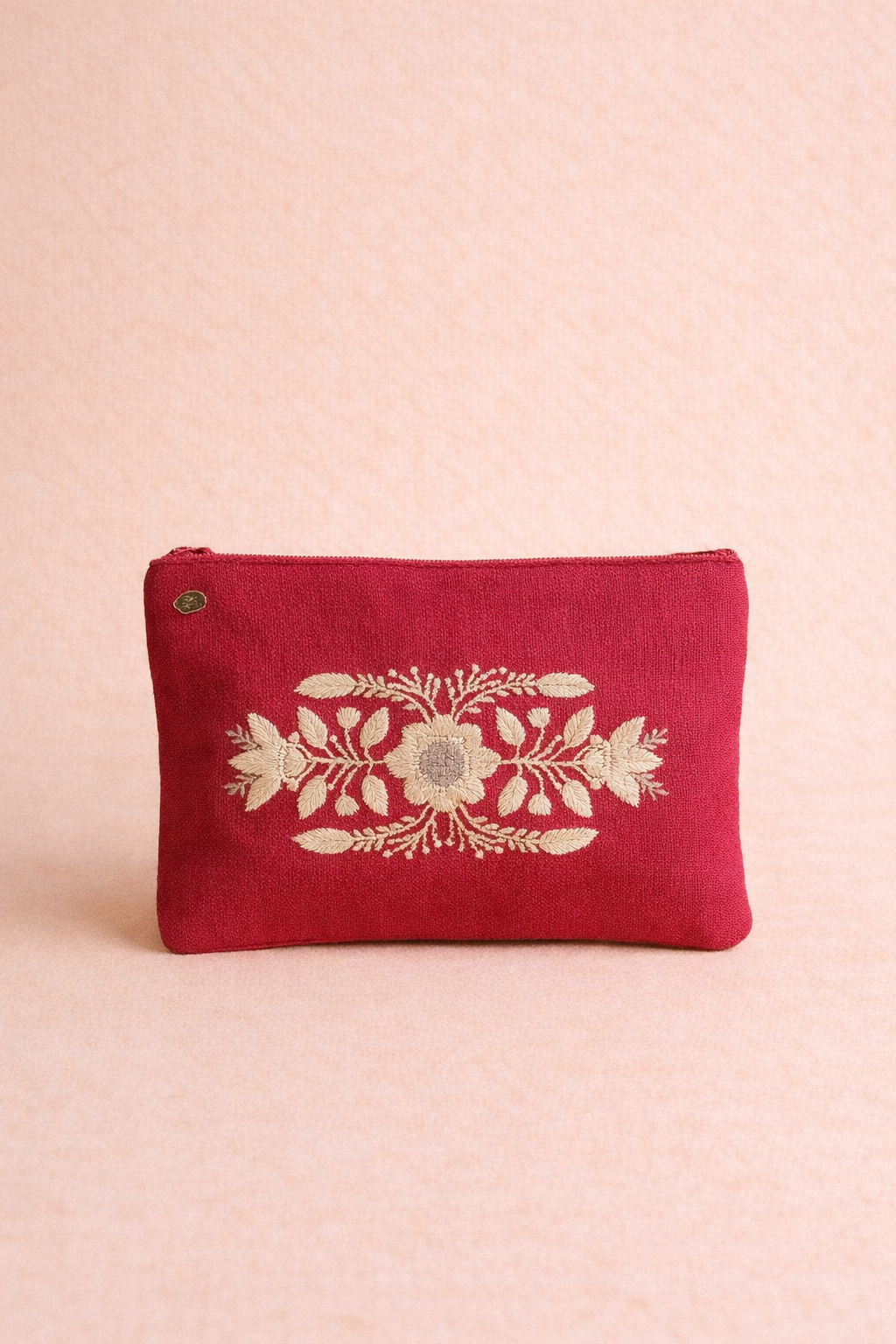 Red pouch with floral embroidery on a pink background