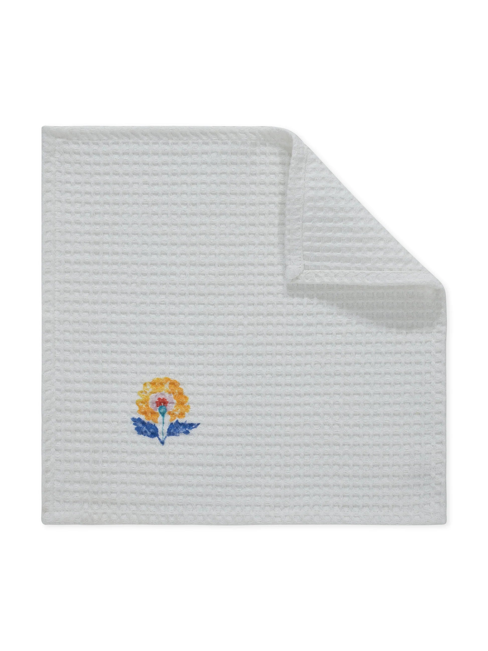White textured towel with embroidered floral design on a white background