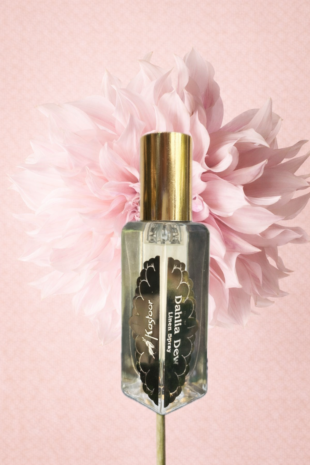 Linen bottle labeled 'Dahlia Dew' with a pink flower in the background on a light pink gradient.