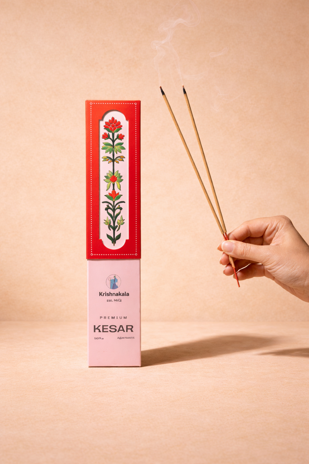 Hand holding incense sticks with  Kesar incense packaging on a beige background