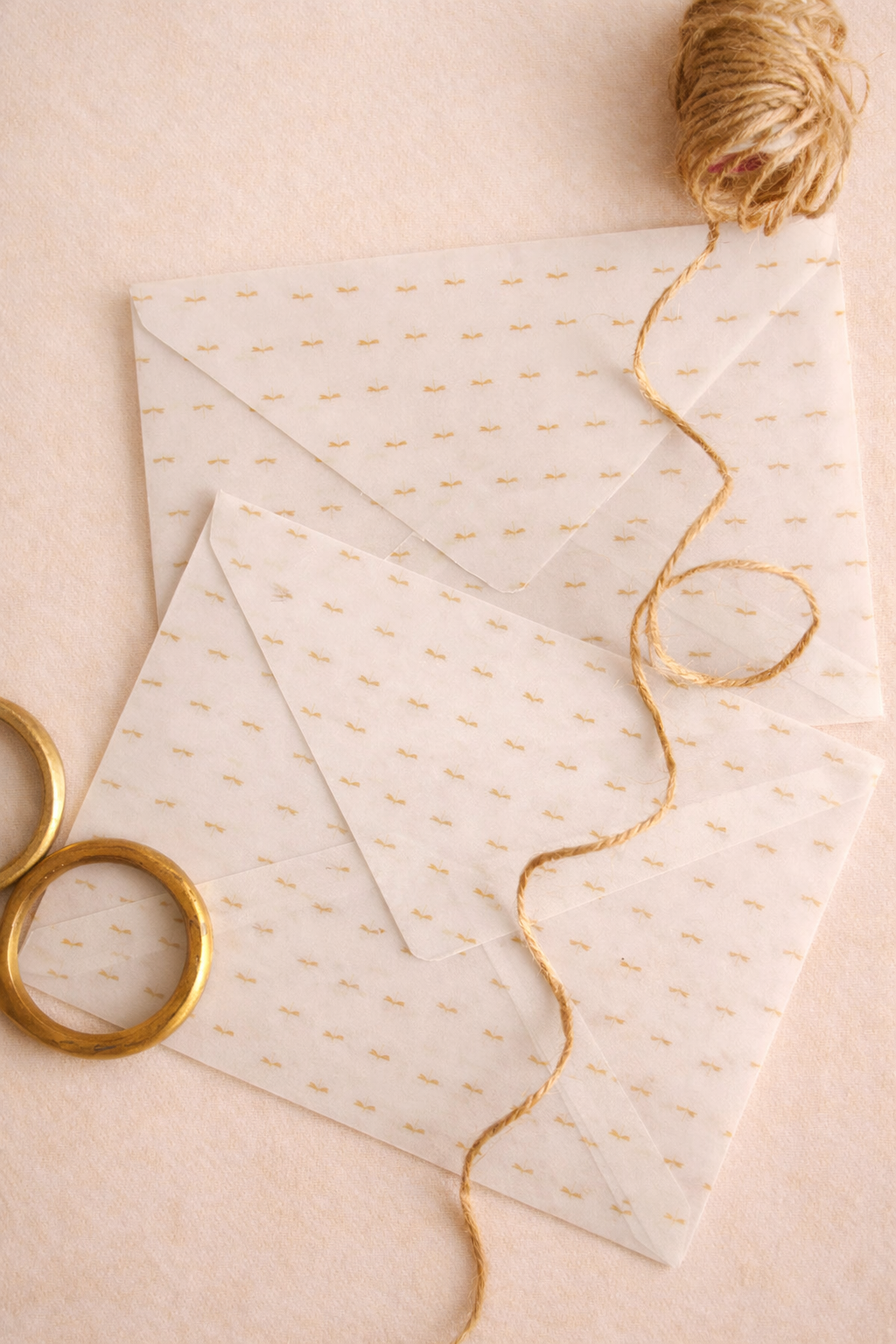 White envelopes with gold text and a ball of twine on a beige background