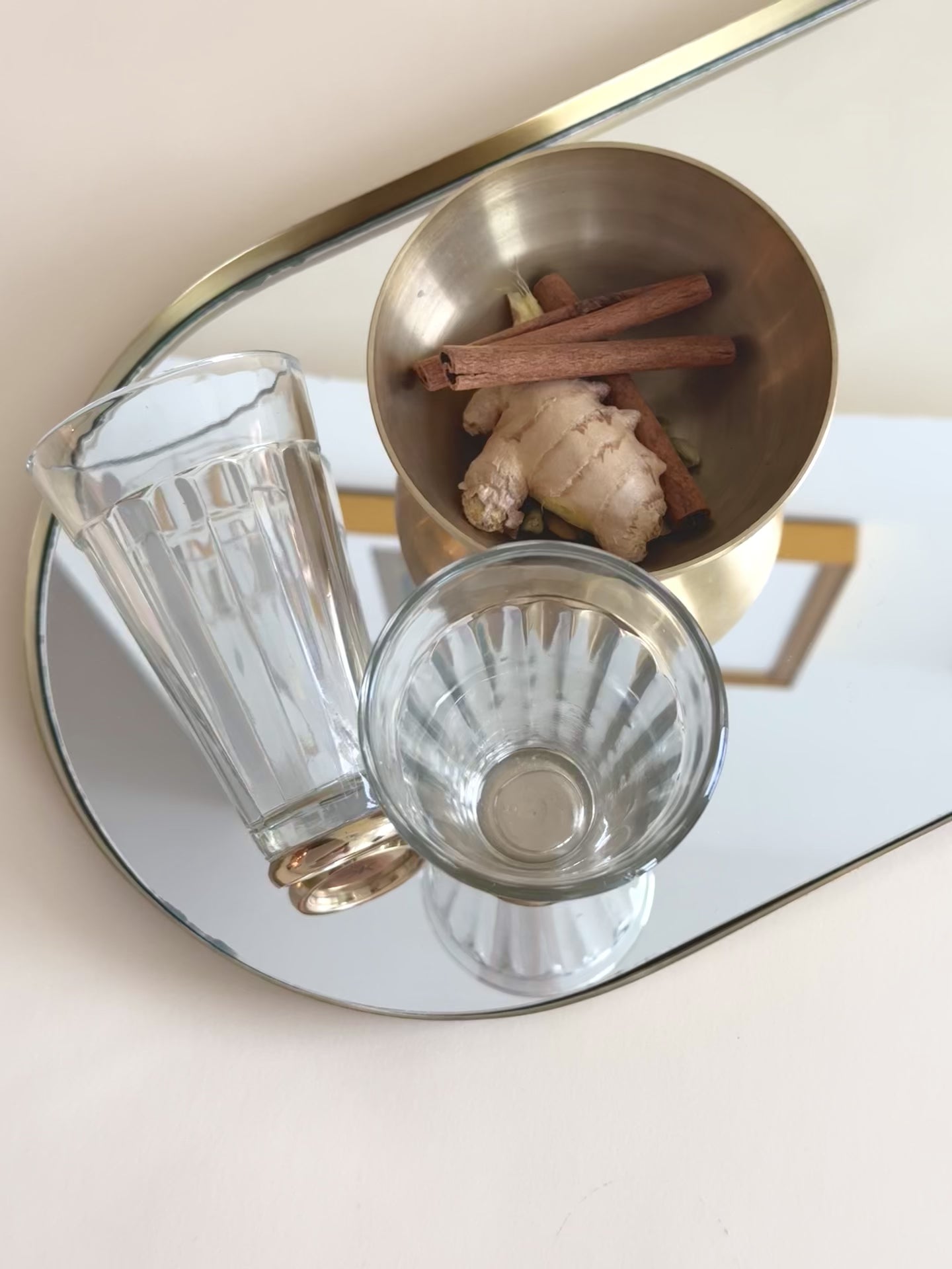 clear glasses placed in a brass tray with spices next to it 