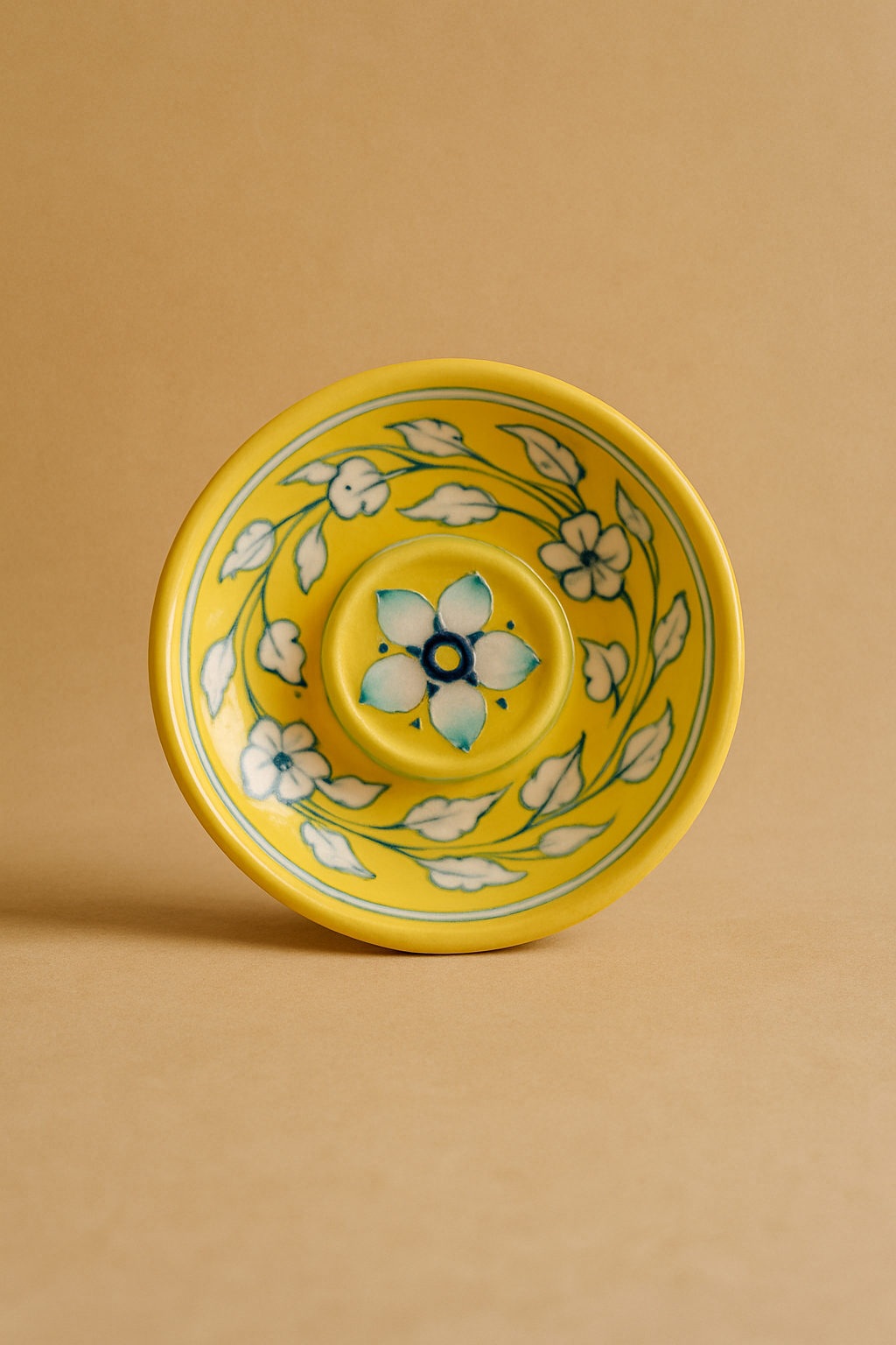 Yellow ceramic incense holder with floral design on a beige background